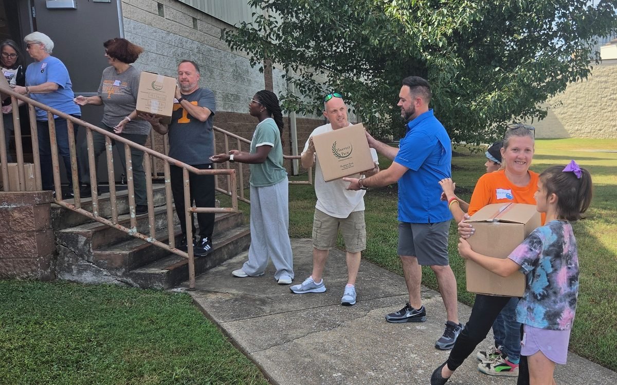 Volunteers of all ages passing Harvest Pack boxes hand to hand down church steps