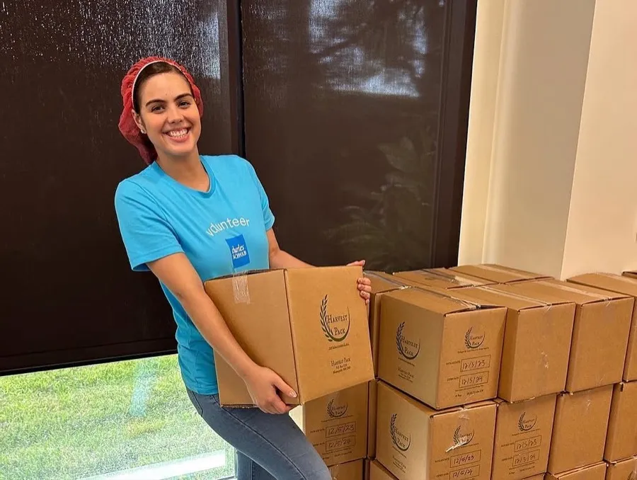 A happy volunteer carrying a packed Harvest Pack meal box
