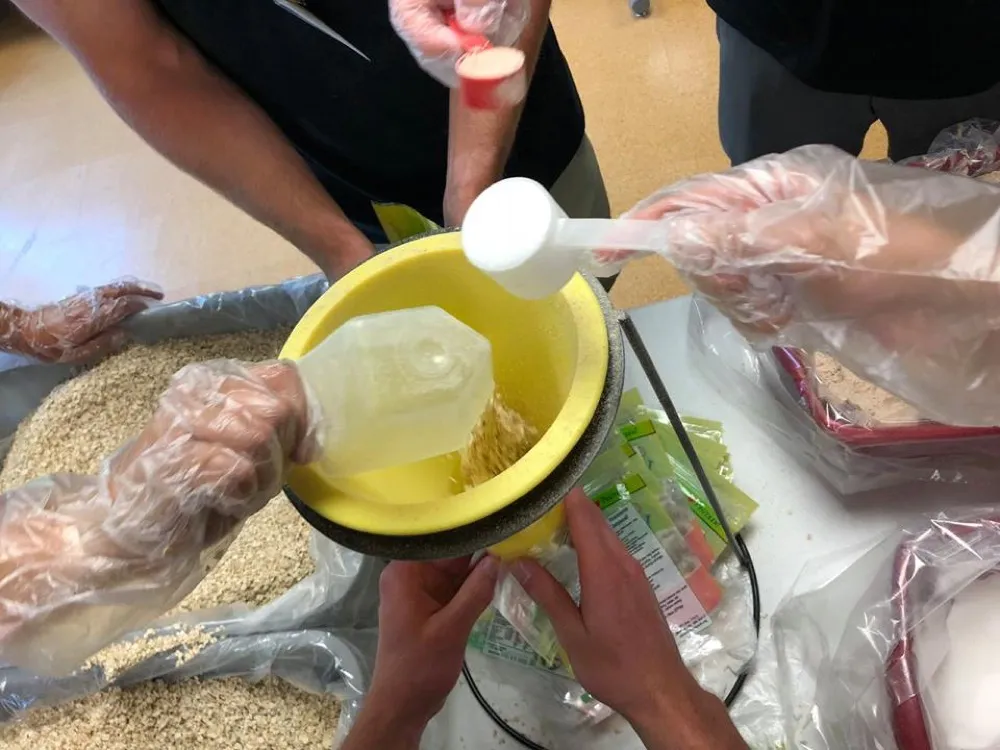 Volunteer scooping fortified oatmeal into a meal pouch