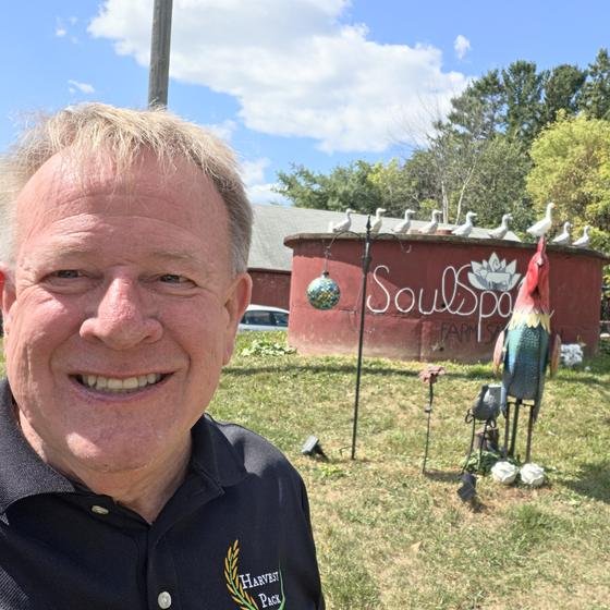 A Harvest Pack team member smiling in front of the SoulSpace sign