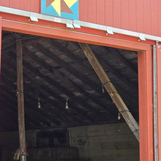 The red barn door with a quilt square above it