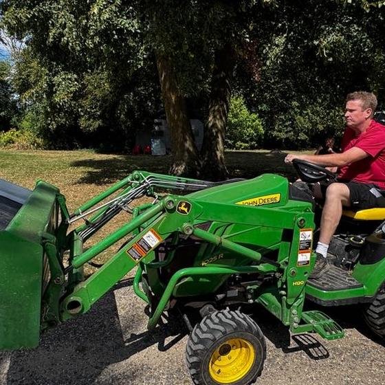 A sanctuary volunteer driving a tractor loaded with bins of donated ingredients